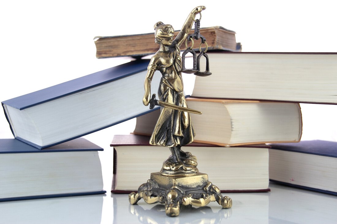 Statuetta della giustizia accanto a volumi di diritto